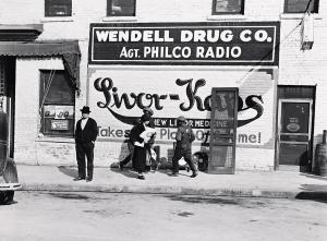 WOLCOTT Marion Post 1910-1990,Advertisement on side of drug store, Wendell Dru,1939,Swann Galleries 2024-02-15